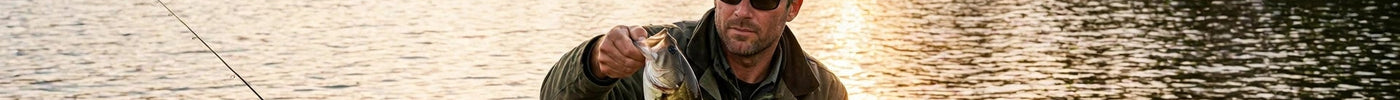 Angler in a small boat holding a smallmouth bass on a northern lake at golden hour