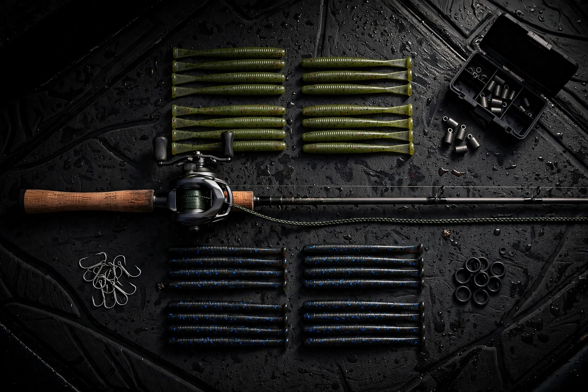 Tackle flat-lay: baitcasting rod, stick worms, wacky hooks, O-rings and weights on a dark boat deck