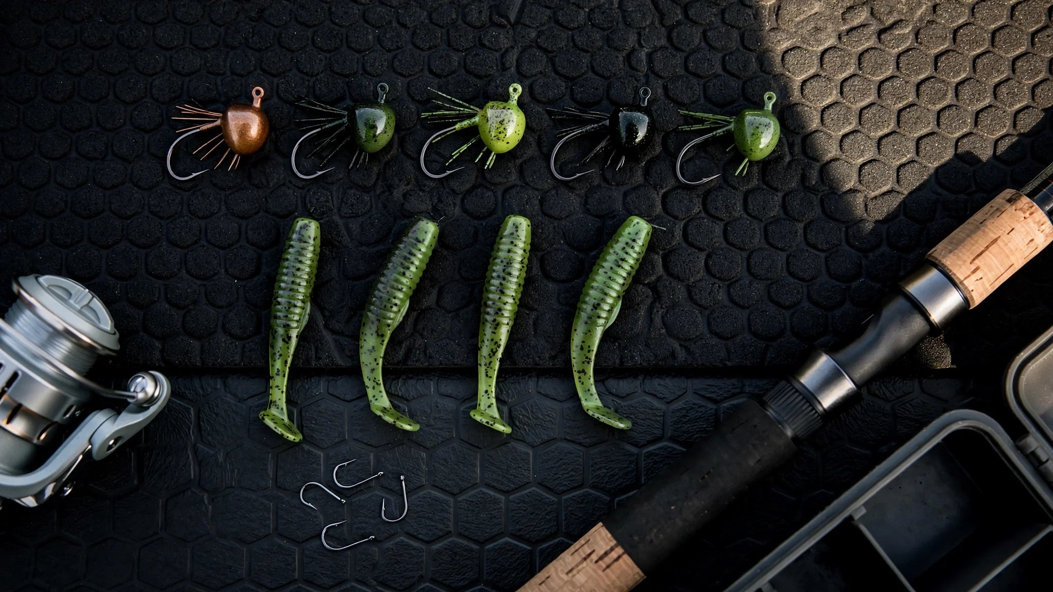 Ned rig tackle flat-lay: mushroom jig heads, finesse worms and hooks on a dark boat deck